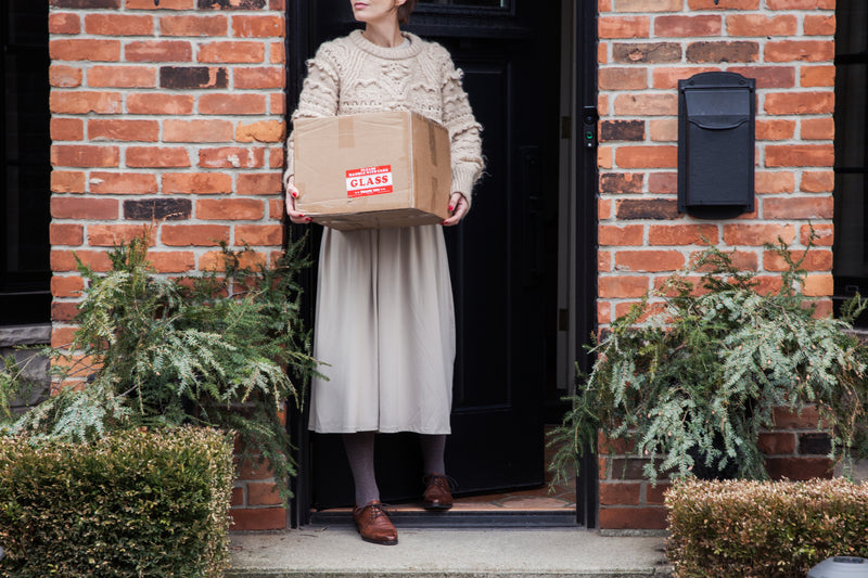 Image of a trendy woman receiving delivery of a package from an online order. Free delivery on orders over €50.